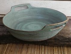 a green bowl sitting on top of a wooden table