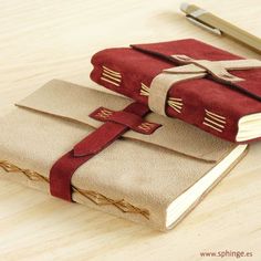 two red and beige books sitting on top of a wooden table next to a pen