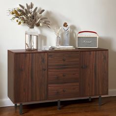 a wooden cabinet sitting on top of a hard wood floor next to a white wall