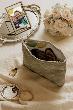 an open purse sitting on top of a bed next to a mirror and ring holder