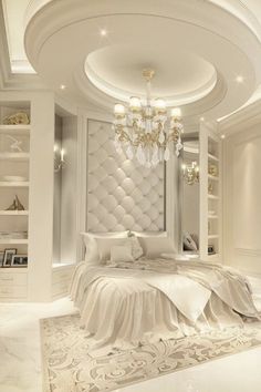 a large white bed sitting under a chandelier in a bedroom