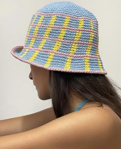 a woman wearing a crocheted hat with blue, yellow and pink squares on it