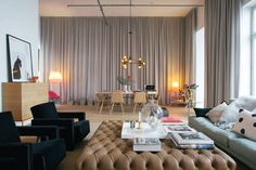 a living room filled with lots of furniture next to a window covered in drapes