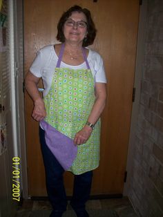 a woman wearing an apron and glasses standing in front of a door