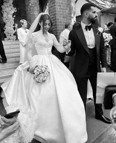 the bride and groom are walking down the stairs together in black and white, holding hands