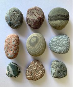 nine rocks arranged in a circle on a white surface, each with different colors and shapes