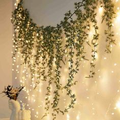 some white vases with plants and lights on them