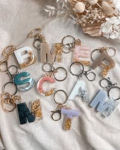 many different types of key chains laying on top of a white blanket next to flowers