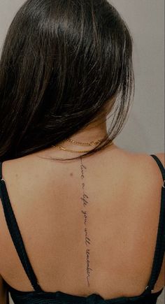 the back of a woman's neck with a small tattoo on her left shoulder