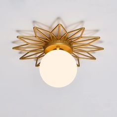 a ceiling light with a white ball hanging from it's center and an intricate design on the top