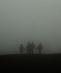 three people are holding hands in the fog