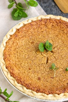 a pie sitting on top of a metal pan covered in green leafy toppings