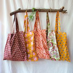 five bags hanging from a tree branch on a white background, each with different patterns