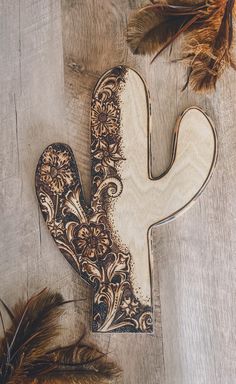 a wooden letter shaped like a cactus with feathers around it