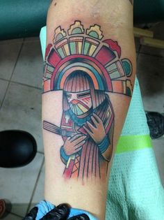 a person with a tattoo on their arm holding a cross and wearing a headdress