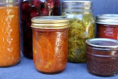 several jars filled with different types of fruit and vegetable jams next to each other