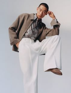 a man sitting on top of a chair wearing white pants and a blazer jacket