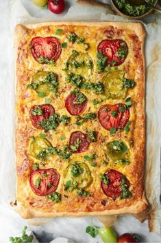 an overhead view of a pizza with tomatoes and broccoli on it, surrounded by other ingredients