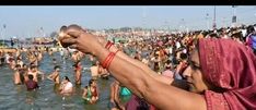 a woman in a sari is holding up a bottle while standing in the water