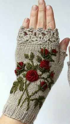 a woman's hand is wearing a knitted glove with roses on it