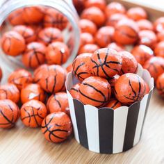 basketball balls are sitting in striped cups on a table