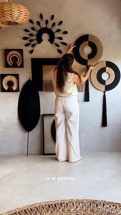 a woman standing in front of a wall with pictures on it and hanging decorations above her