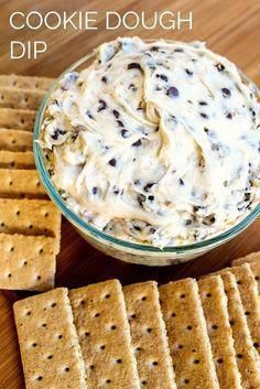 cookie dough dip in a glass bowl surrounded by crackers on a wooden table with text overlay