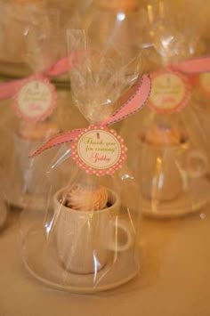 small cupcakes wrapped in cellophane and tied with pink ribbon are on the table