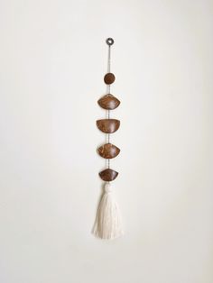 a wall hanging with stones and tassels attached to it's side on a white wall