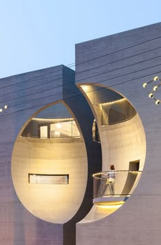 a person standing on a balcony next to a building with a spiral shaped structure in the middle