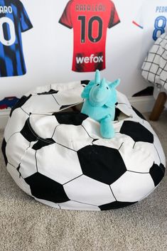 a bean bag chair with a stuffed elephant on top of it in front of soccer jerseys