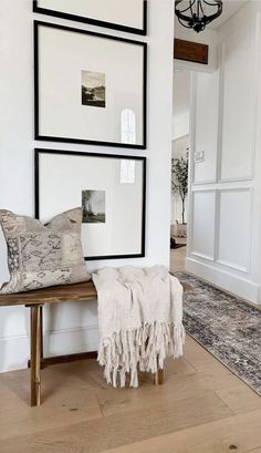 a wooden bench sitting in the middle of a room next to pictures on the wall