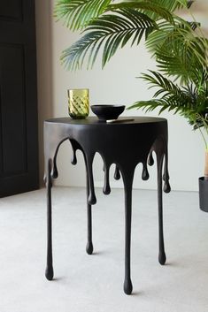 a black table sitting next to a potted plant on top of a white floor