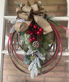 a wreath hanging on the front door with pine cones, berries and evergreens attached to it