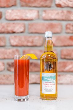 a bottle of alcohol sitting next to a glass filled with liquid and a lemon slice