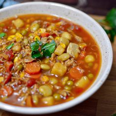 a white bowl filled with vegetable soup on top of a wooden table