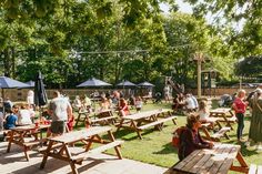 many people are sitting at picnic tables in the park