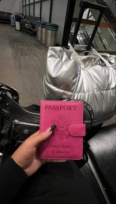 a pink passport sitting on top of a black bag next to a silver handbag