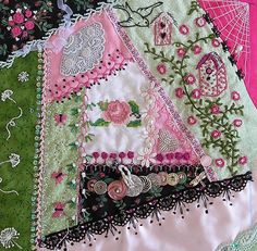 many different types of fabric and laces are on the table top, with pink flowers in the background