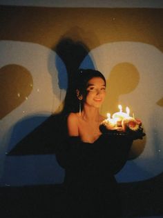 a woman holding a cake with lit candles