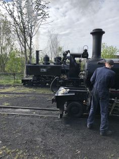 a man standing next to an old fashioned train