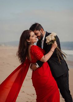 a man in a tuxedo hugging a woman on the beach