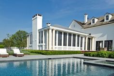 a house with a swimming pool in front of it and lawn furniture around the pool