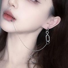 a woman with long black hair wearing silver chains on her ear and nose piercings