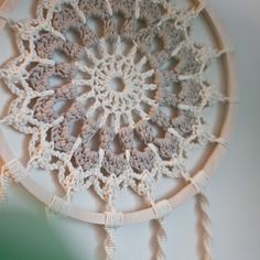 a crocheted doily hanging on the wall with tassels around it