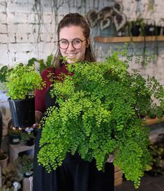 a woman holding two potted plants in front of her face and smiling at the camera