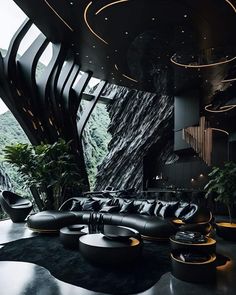 a living room filled with black furniture next to a tall wall covered in greenery