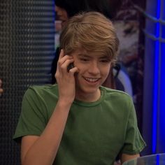 a young boy talking on a cell phone while sitting at a table in front of him