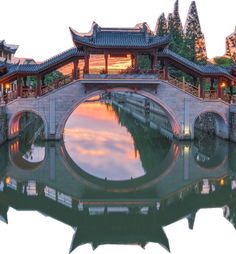 a bridge over a body of water with buildings on either side and trees in the background