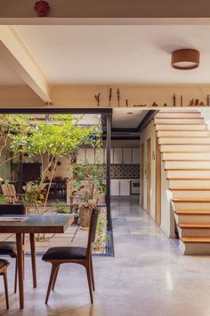 a dining room with stairs leading up to the second floor and an open living area